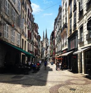 a street with people walking down a street with buildings at Hotel Le Port Neuf in Bayonne