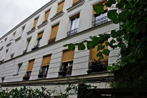 a white building with windows and potted plants on it at 25 Rue du Télégraphe in Paris