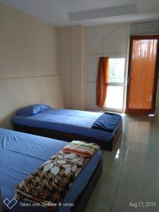 a bedroom with two beds and a window at Rumah Sakinah in Wonosobo