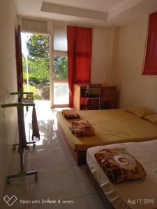 a bedroom with two beds and a window and a desk at Rumah Sakinah in Wonosobo