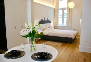 根特Bennestay的一间卧室配有床和一张桌子,桌子上摆放着眼镜和鲜花
