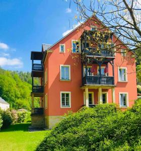 een groot oranje huis met een balkon op een heuvel bij Villa Monsei in Bad Schandau