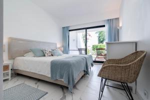 a bedroom with a bed and a chair and a window at Victory Village 1B Quinta do Lago in Quinta do Lago