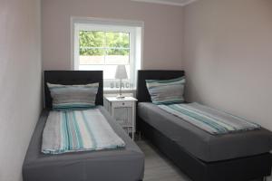 2 Betten in einem kleinen Zimmer mit Fenster in der Unterkunft Op'n Dörp Apartments in Barsbek