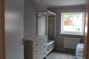 a bedroom with a white dresser and a window at Op'n Dörp Apartments in Barsbek