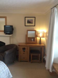 a room with a desk with a mirror and a television at Furan GuestHouse in Inverness