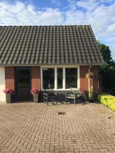 una casa de ladrillo con dos bancos en un patio en De Wolbert en Wapenveld