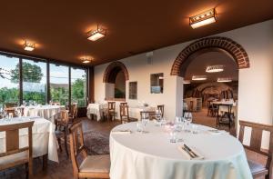 um restaurante com mesas e cadeiras brancas e janelas em Il Vigneto em Roddi