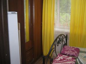 a room with a bed and a window with yellow curtains at Apartment in Pyatigorsk in Pyatigorsk