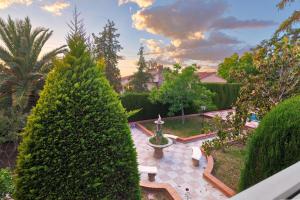 Blick auf einen Garten mit einem Brunnen und Bäumen in der Unterkunft NEW. LUXURY VILLA C&C. JARDÍN, PISCINA Y BARBACOA in Granada