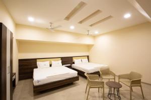 帕拉尼Ponnis Hotel的有两张床、一张桌子和几把椅子的房间