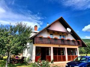 a house with a balcony and a car parked in front at Apartments & rooms Velebit in Lovinac