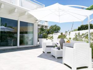 a white patio with white chairs and an umbrella at Arneo Terra del Sole in Torre Lapillo