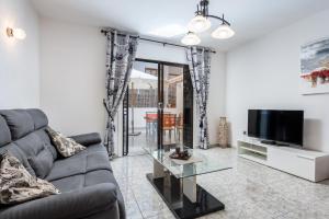 a living room with a couch and a tv at Victoria Court Modern 1 Bed Apartment Los Cristianos Tenerife in Los Cristianos