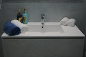 un lavandino in bagno con asciugamani e una bottiglia di sapone di Oliver's House Sardinia a Flumini di Quartu