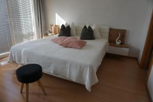 - une chambre dotée d'un lit blanc avec des oreillers et une chaise dans l'établissement Living Apartment Central, à Merano