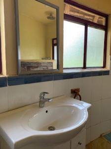 lavabo blanco en el baño con espejo en Samuka Island Retreat, en Jinja