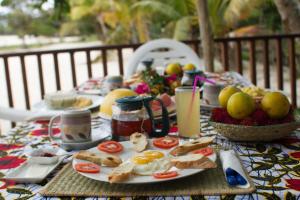a breakfast table with eggs and bread and fruit at Les Acacias Bungalows in Manambato