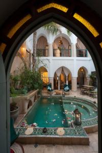 uma grande piscina num edifício com uma arcada em Riad la Cle de la Medina, location en exclusivite em Marrakech