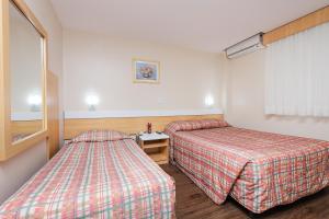 a hotel room with two beds and a window at Hotel Express Terminal Tur - Rodoviária Porto Alegre in Porto Alegre