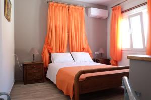 una camera da letto con un letto con tende arancioni e una finestra di Kalderimi Home a Calimno (Kalymnos)