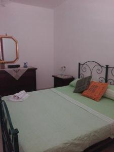 a bedroom with a green bed and a mirror at Casa della camperia in Favignana