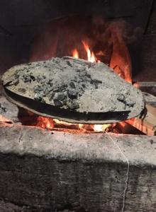 a pizza sitting on top of a fire at "Frogs House" Hotel & Restorant Slow Food in Lushnjë