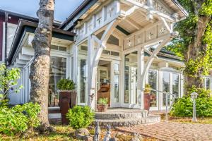 ein Haus mit einer Veranda mit Fenstern und einem Baum in der Unterkunft Pension Linde Prerow in Prerow