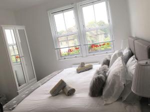 a white bed with pillows and comforter with two windows at Number One in Wetherby