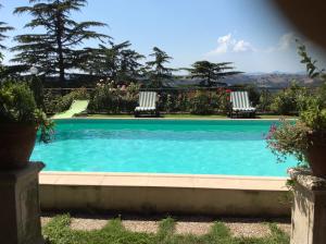 una piscina con 2 sillas de césped y flores en Villa Covaccioli Schimperna, en Formello