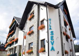 um hotel com flores ao lado de um edifício em Vila Seva em Vatra Dornei