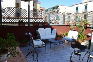 a patio with white chairs and tables and plants at B&B Olania in Castellammare di Stabia