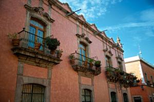 Un edificio con balcones y plantas en macetas. en La Casa de la Marquesa, en Querétaro