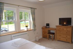 a bedroom with a bed and a dresser with a television at East Park B&B in Roybridge