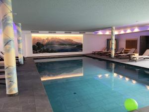 uma piscina com cadeiras e um quadro na parede em Hotel Gasthof Weiherbad em Villabassa