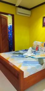 a bed in a room with a yellow wall at OYO 938 Citrine Travel Lodge in El Nido