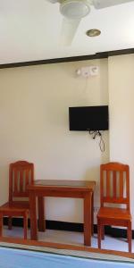 two chairs and a table and a tv on a wall at OYO 938 Citrine Travel Lodge in El Nido