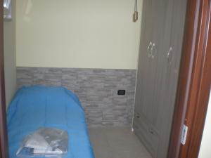Dormitorio pequeño con cama azul y pared de ladrillo en ARCOBALENO, en Mondragone