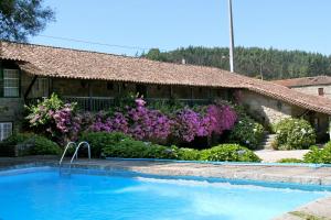 a house with a swimming pool and purple flowers at Quinta de S.Vicente in Geraz do Minho