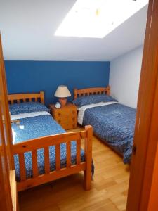 two beds in a bedroom with blue walls at Dúplex Casabó in Camprodon