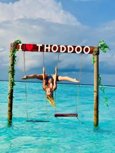 Una mujer está en un columpio en el agua en Relax Lodge, en Thoddoo