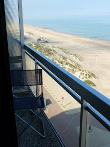 a balcony with a chair and a beach at Zon, zee en ontspanning in Middelkerke
