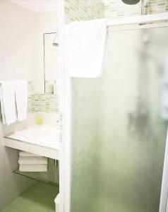 uma casa de banho branca com um lavatório e um chuveiro em Casa Lu Salentu em Torre Lapillo