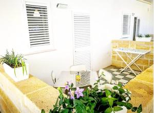 a balcony with plants and a table and two windows at Casa Lu Salentu in Torre Lapillo