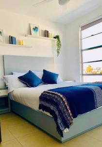 1 dormitorio con 1 cama grande con almohadas azules en Boho Condominium and Unique Comfort in Tijuana, en Tijuana