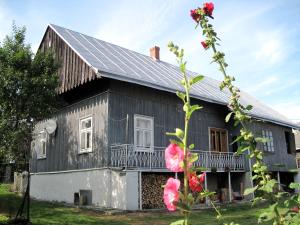 a black and white house with pink flowers in front of it at Chata Pod Kamieniem in Jaśliska