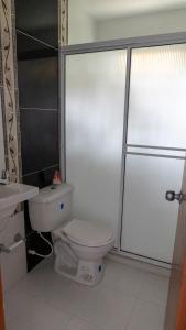 Un baño blanco con inodoro y ducha. en Villa Laura, en Santa Marta