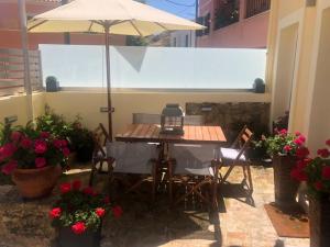 Anemomilos Jacuzzi Suite في مدينة كورفو: طاولة وكراسي مع مظلة على الفناء