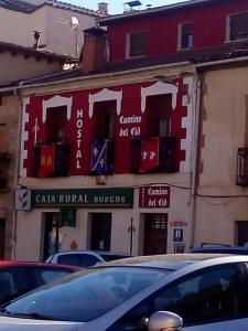 czerwono-biały budynek z samochodami zaparkowanymi przed nim w obiekcie Hostal Camino Del Cid w mieście Huerta del Rey