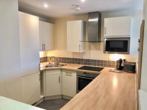 a kitchen with white cabinets and a sink at The Paramount, Swindon in Swindon